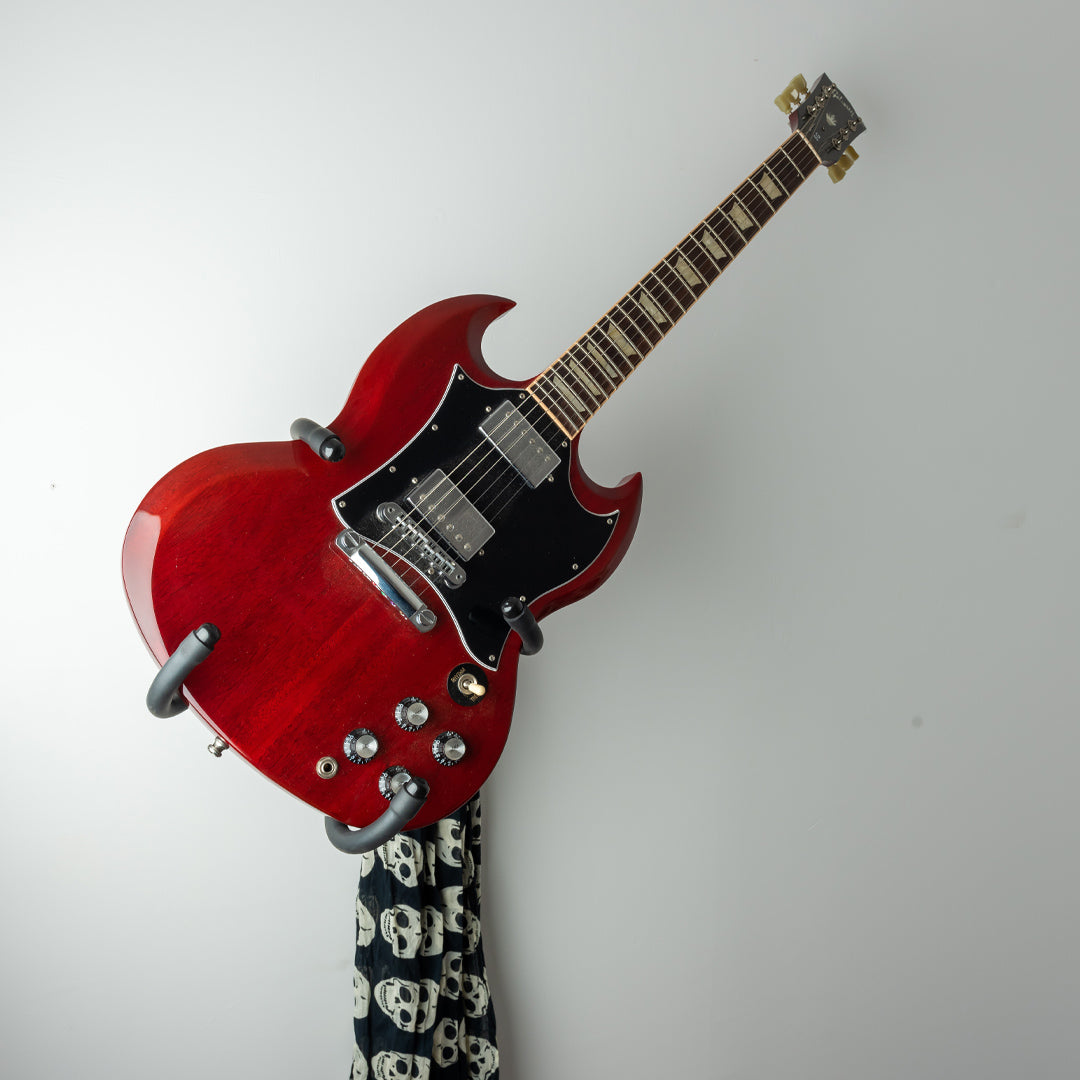 Red electric guitar displayed diagonally on an Iron Cage mount